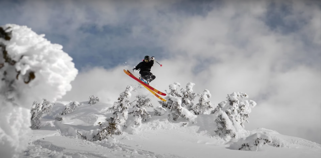 snowflike - la skieuse Emma Dalhstrom en plein saut dans la poudreuse au milieu des sapins enneigés. Image issue du film Skivas.