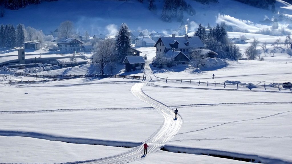 Piste de ski nordique traversant un village enneigé.