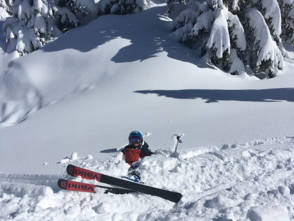 Jeune skieur en skis Völkl allongé dans la neige fraîche et poudreuse.