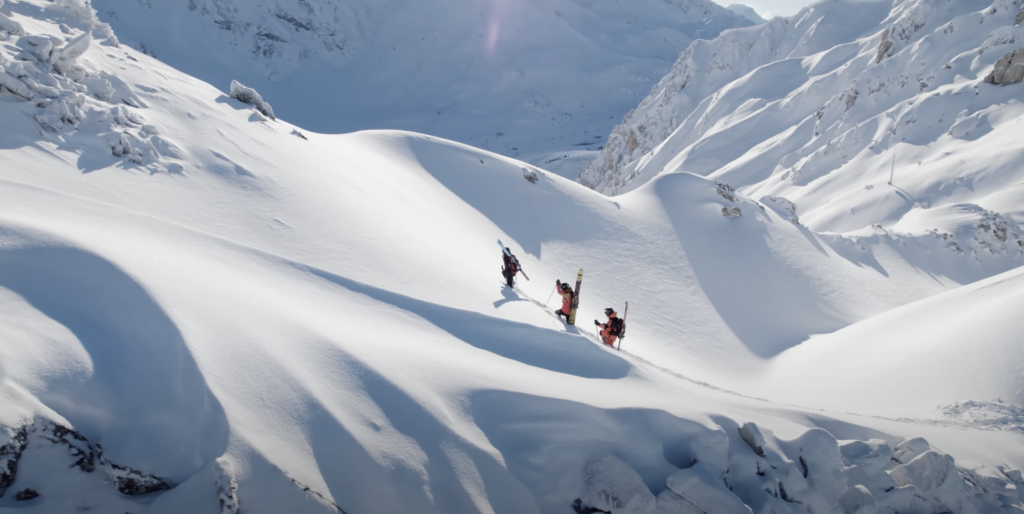 Freerideuses en train de remonter à pied dans la neige frâche, skis sur le dos.